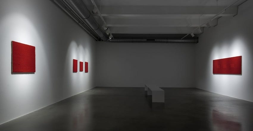 An empty gallery with blank red canvasses on the walls