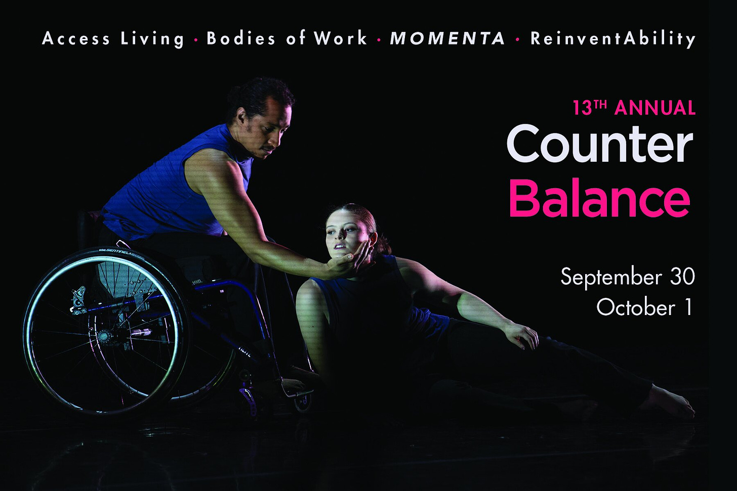 Two dancers, Robby and Tatiana, both wear blue shirts and black pants. Robby, angled towards the right, leans forward in his wheel chair and reaches his right arm towards Tatiana on the floor. Tatiana leans on her side into Robby with her face cupped