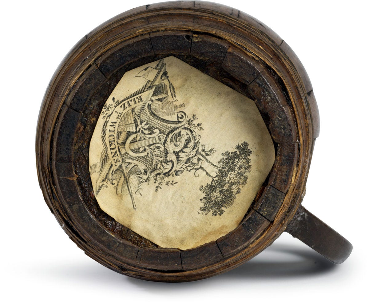 The base of a 17th Cenutry wooden beer mug with a piece of paper printed with a coat of arms stuck to the base The base of a 17th Cenutry wooden beer mug with a piece of paper printed with a coat of arms stuck to the base