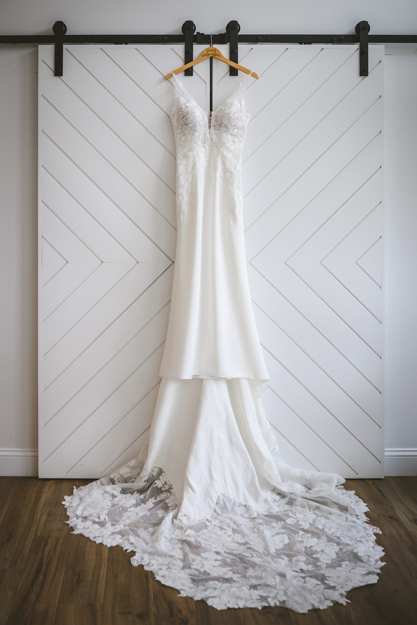 A wedding dress hung in front of sliding, white barn doors