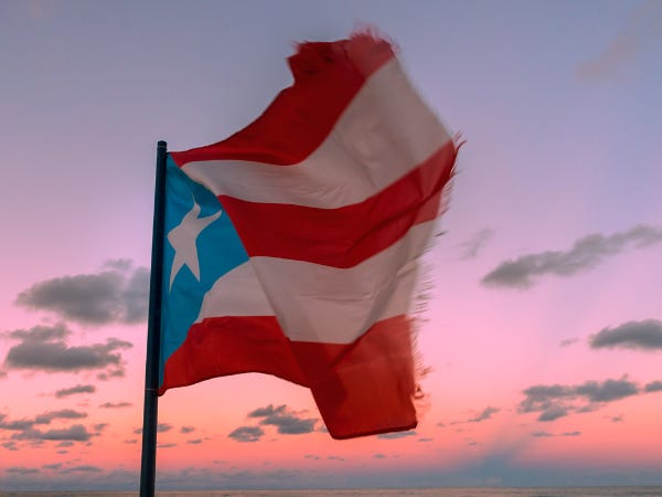 A frayed Puerto Rican flag waving at sunset