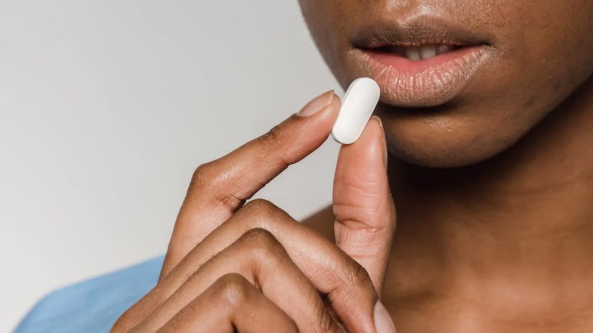close-up of black woman taking white pill