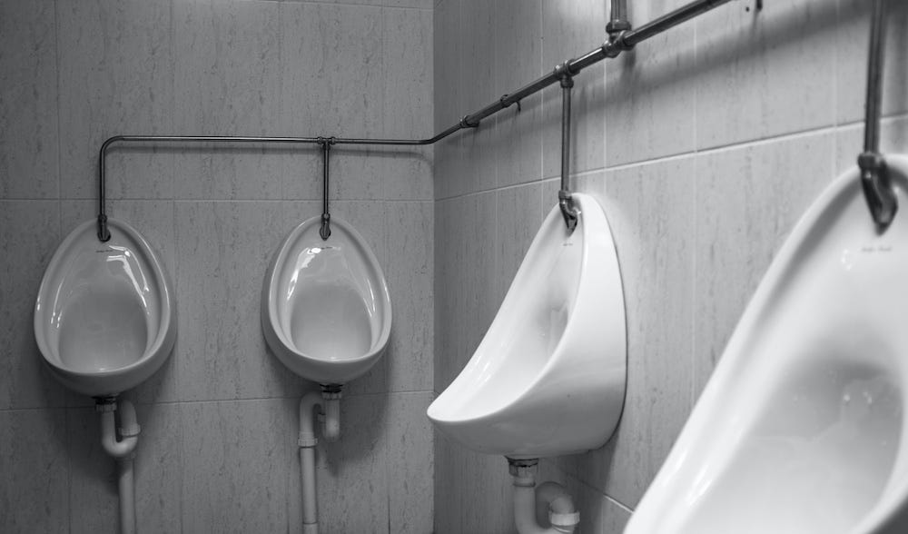 Black and white photo of four urinals