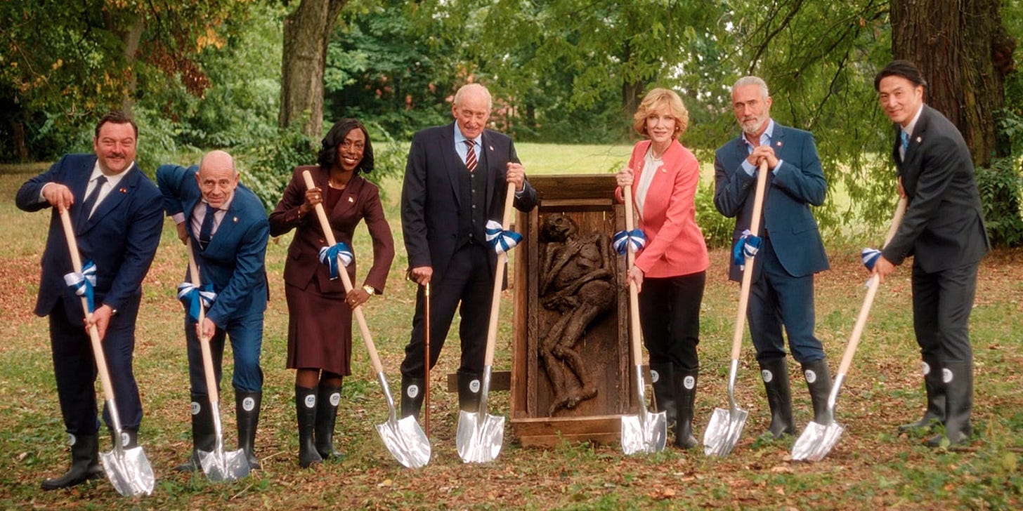 Seven world leaders posing for a photo with spades in the ground: France's Sylvain Broulez (Denis Menochet), Italy's Antonio Lamorte (Rolando Ravello), the United Kingdom's Cardosa Dewindt (Nikki Amuka-Bird), the United States' Edison Wolcott (Charles Dance), Germany's Hilda Ortmann (Cate Blanchett), Canada's Maxime Laplace (Roy Dupuis) and Japan's Tatsuro Iwasaki (Takehiro Hira)