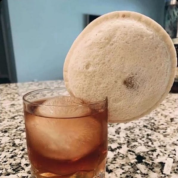 a glass of bourbon garnished with an Uncrustable