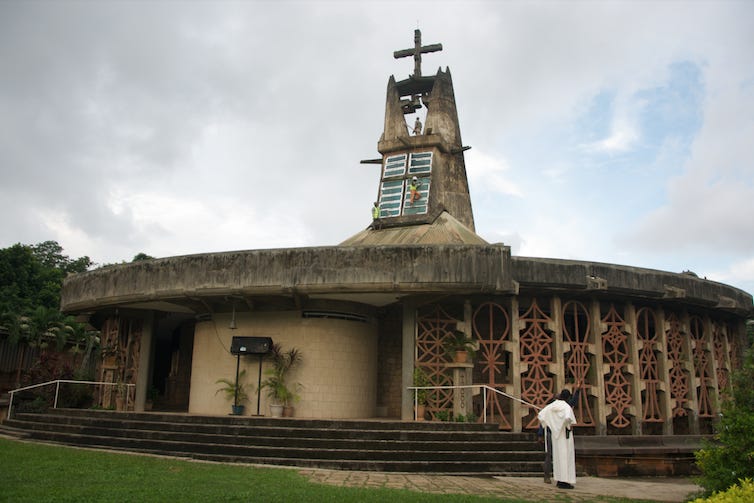 A round church like structure with a rustic spire and ornamental detail of African symbols.