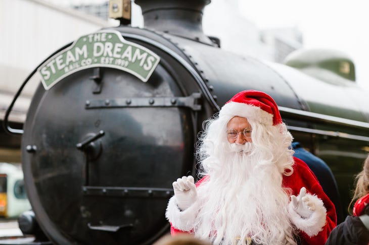 Santa standing in front of a steam train