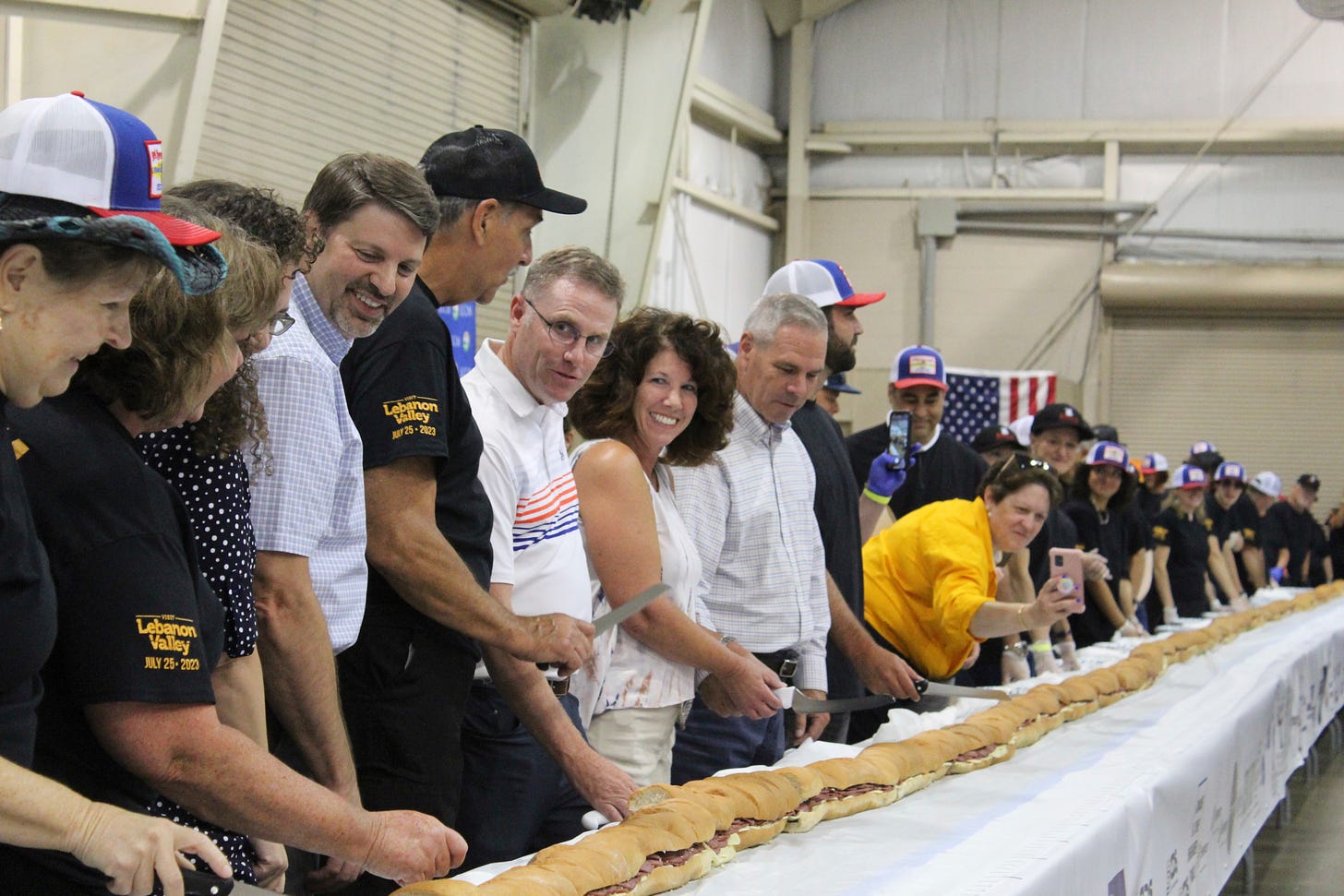 Volunteers help assemble the 150-foot-long (45.7-meters-long) bologna sandwich at the Lebanon Area Fair on Tuesday, July 25, 2023 in Lebanon, Pa. Every footlong “bite” was sponsored at $100 per foot.