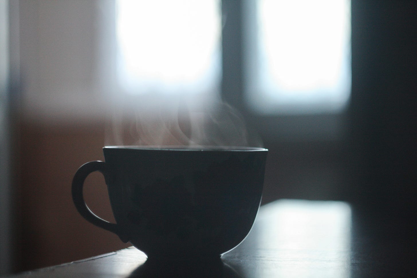 A silhouette of a coffee cup with steam rising.