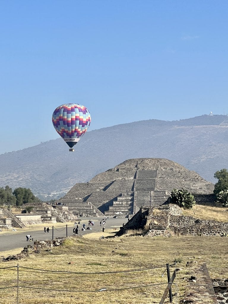 pyramid at teotihuacan with a hot air balloon flying over 