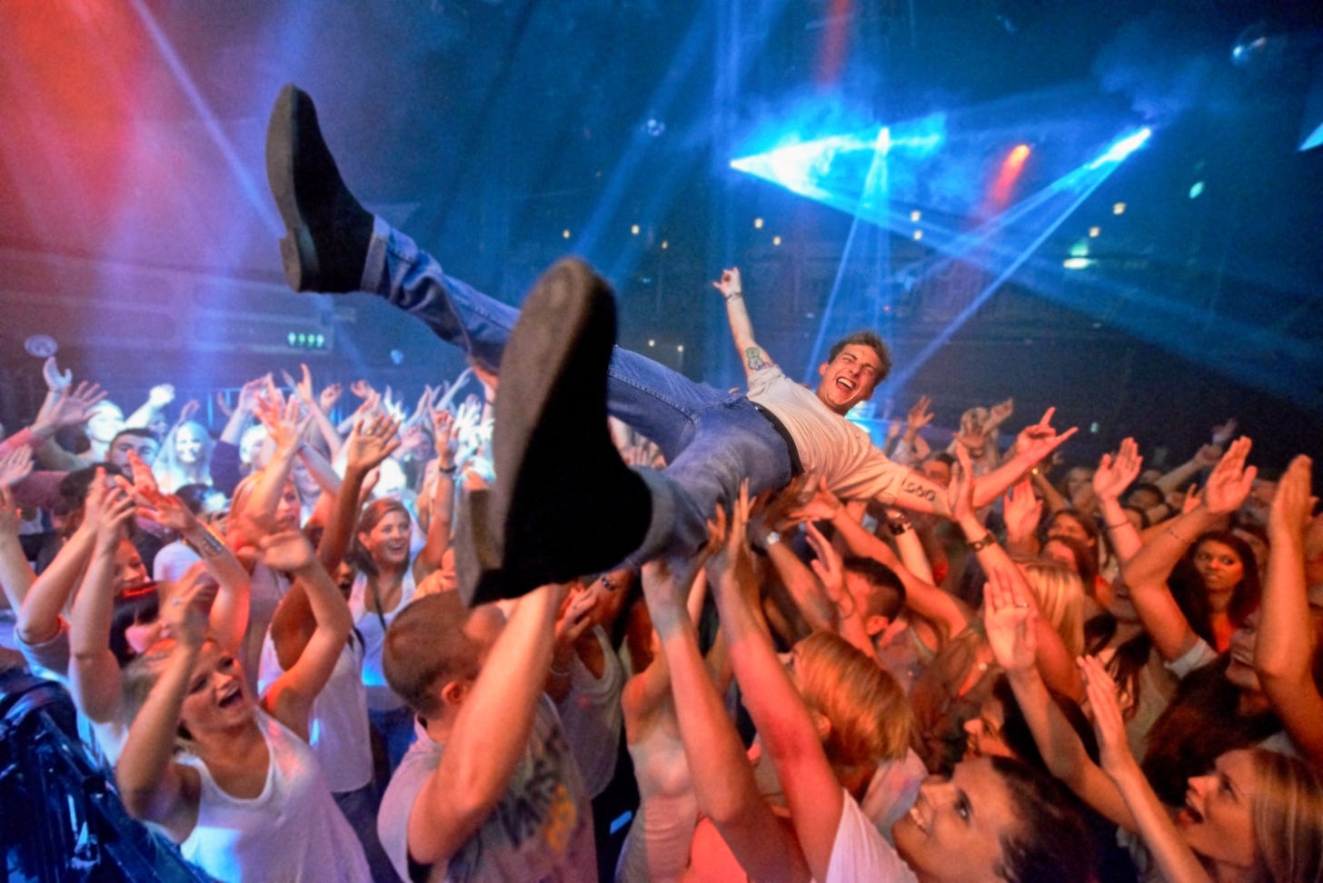 Smiling man being held aloft in a mosh pit