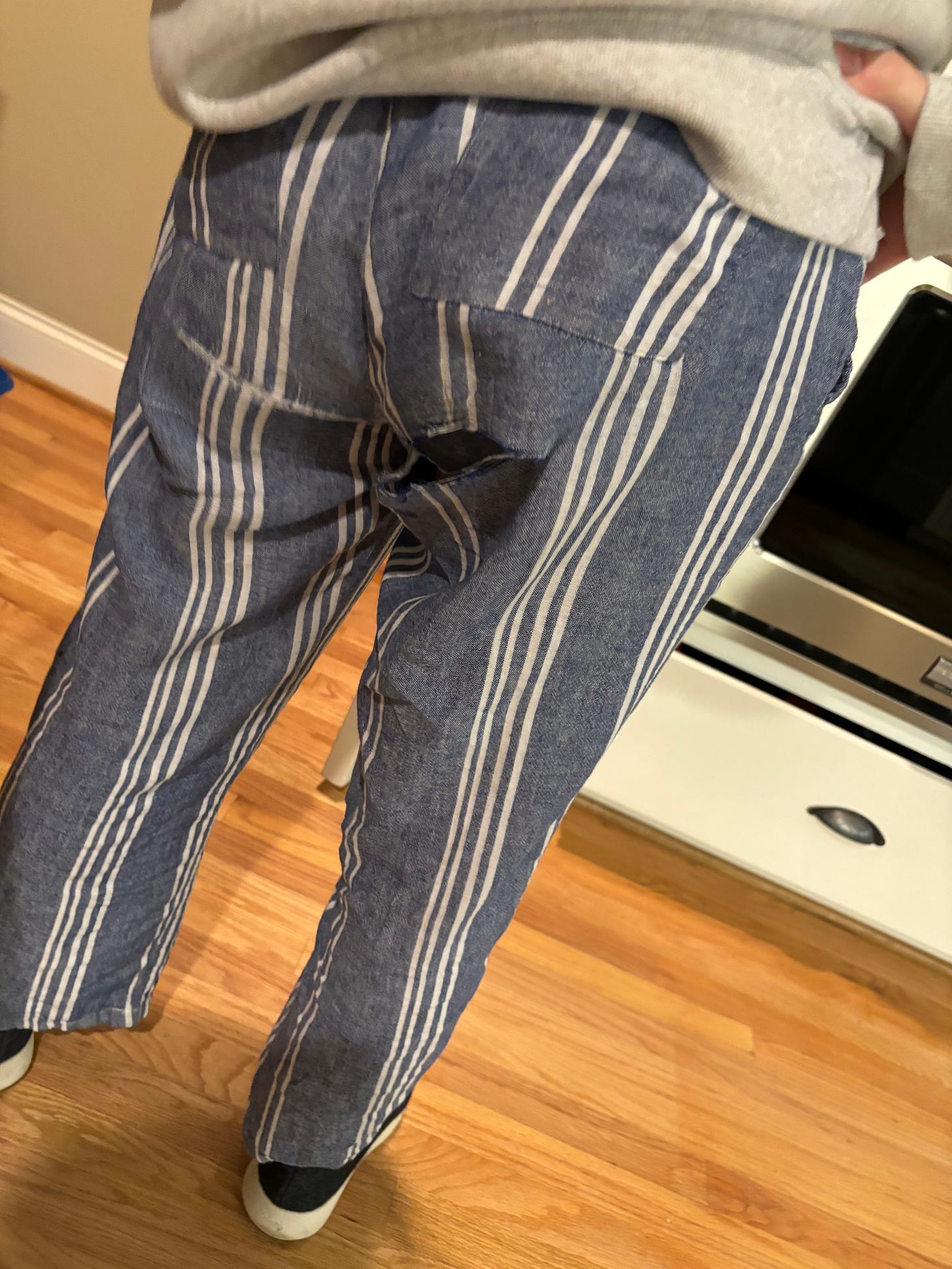 The author’s blue stiped linen pants, photo taken from behind, with a rip in the butt