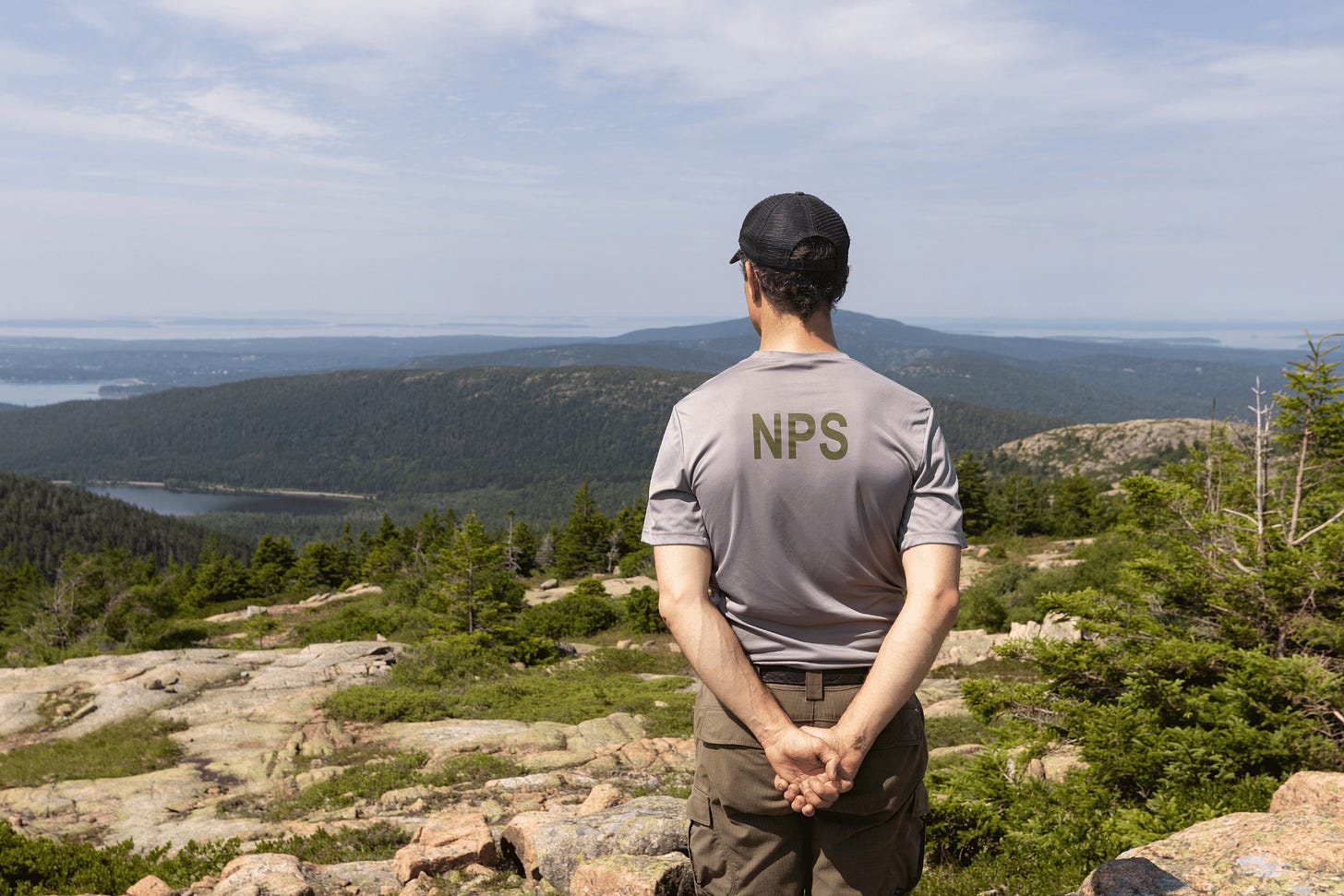 A National Park Service employee looks out at the view from Sargent Mountain