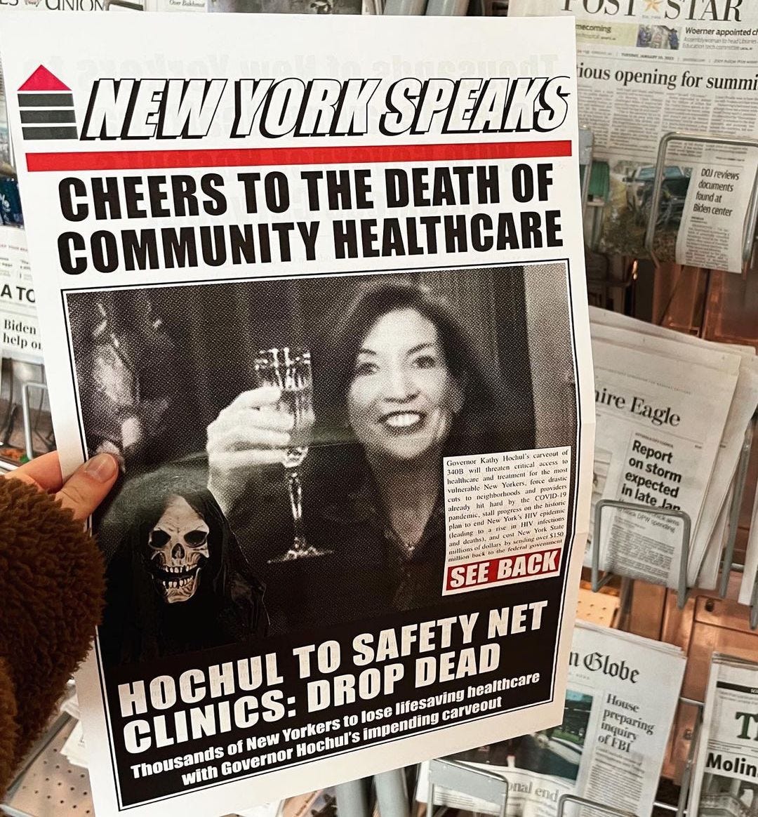 A newspaper called NEW YORK SPEAKS has an image of Kathy Hochul raising a glass of champagne. “Cheers to the death of community healthcare / Hochul to safety net clinics: Drop dead.”