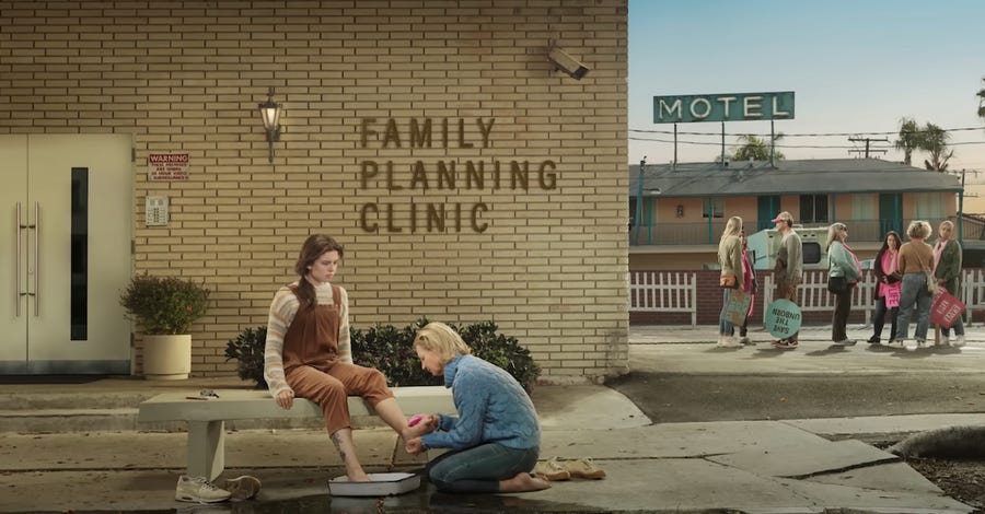 Girl washing another girl's feet in front of family planning clinic