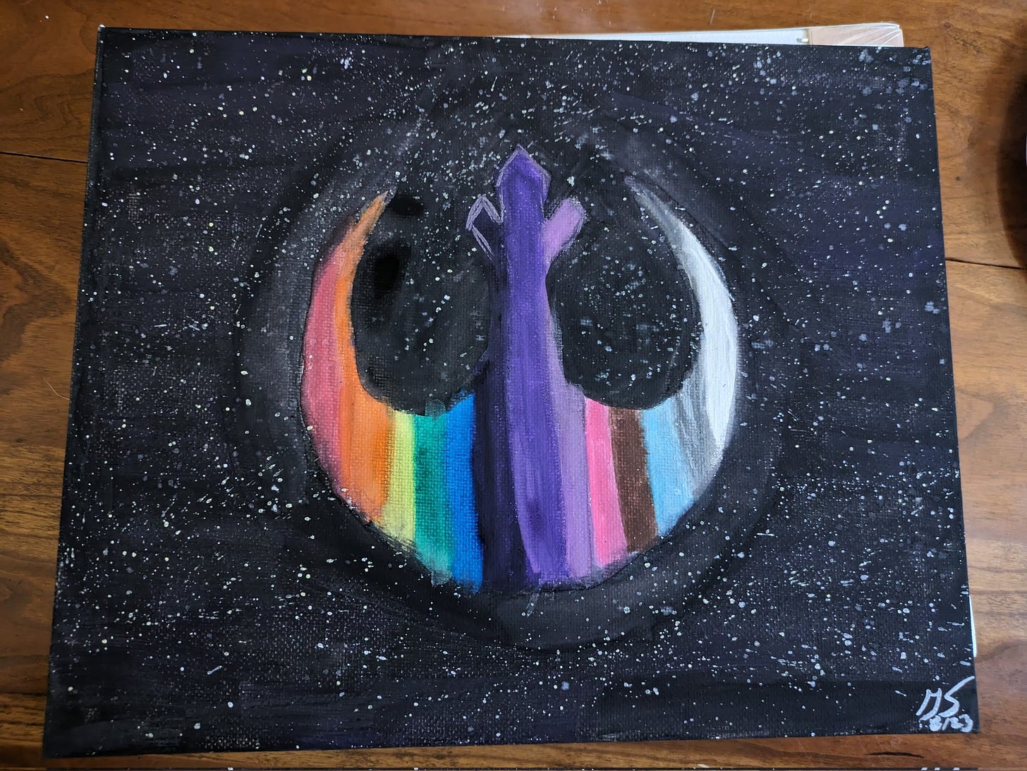 A painting of a rebel alliance symbol with rainbow and trans colors set against a starry background 