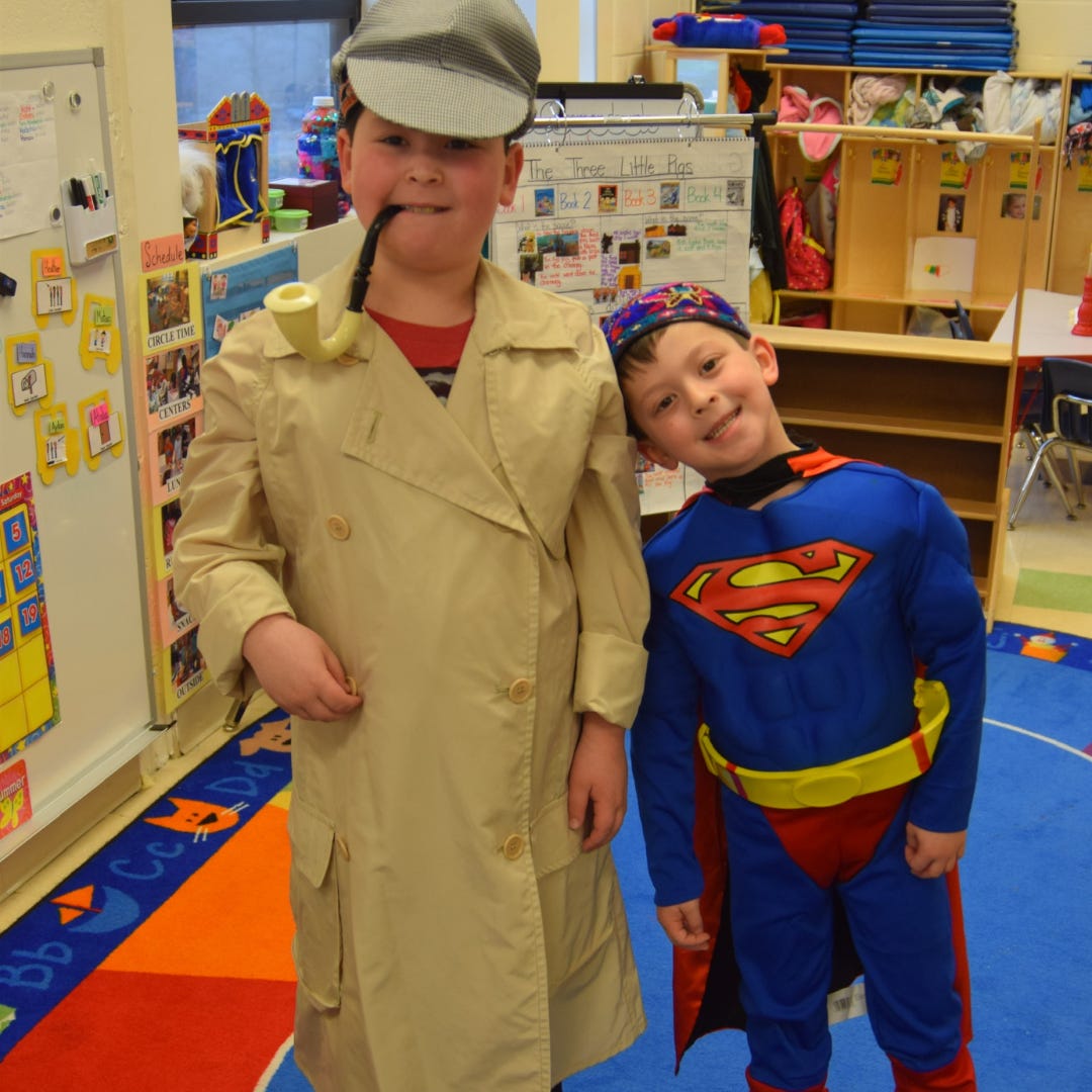 Rafi is dressed in a detective suit next to another student in a Superman costime