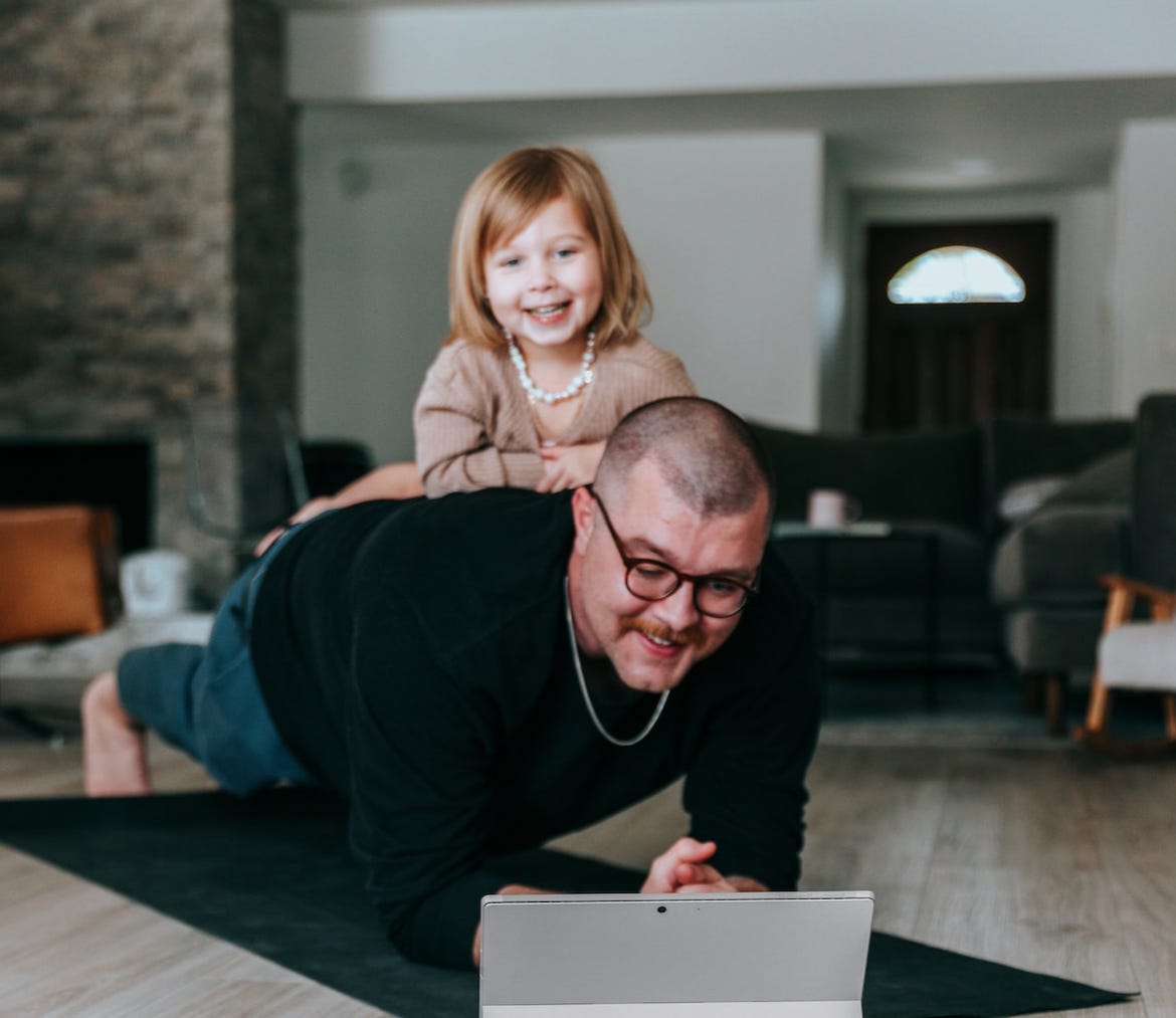A father doing planks with his little kid as added weight