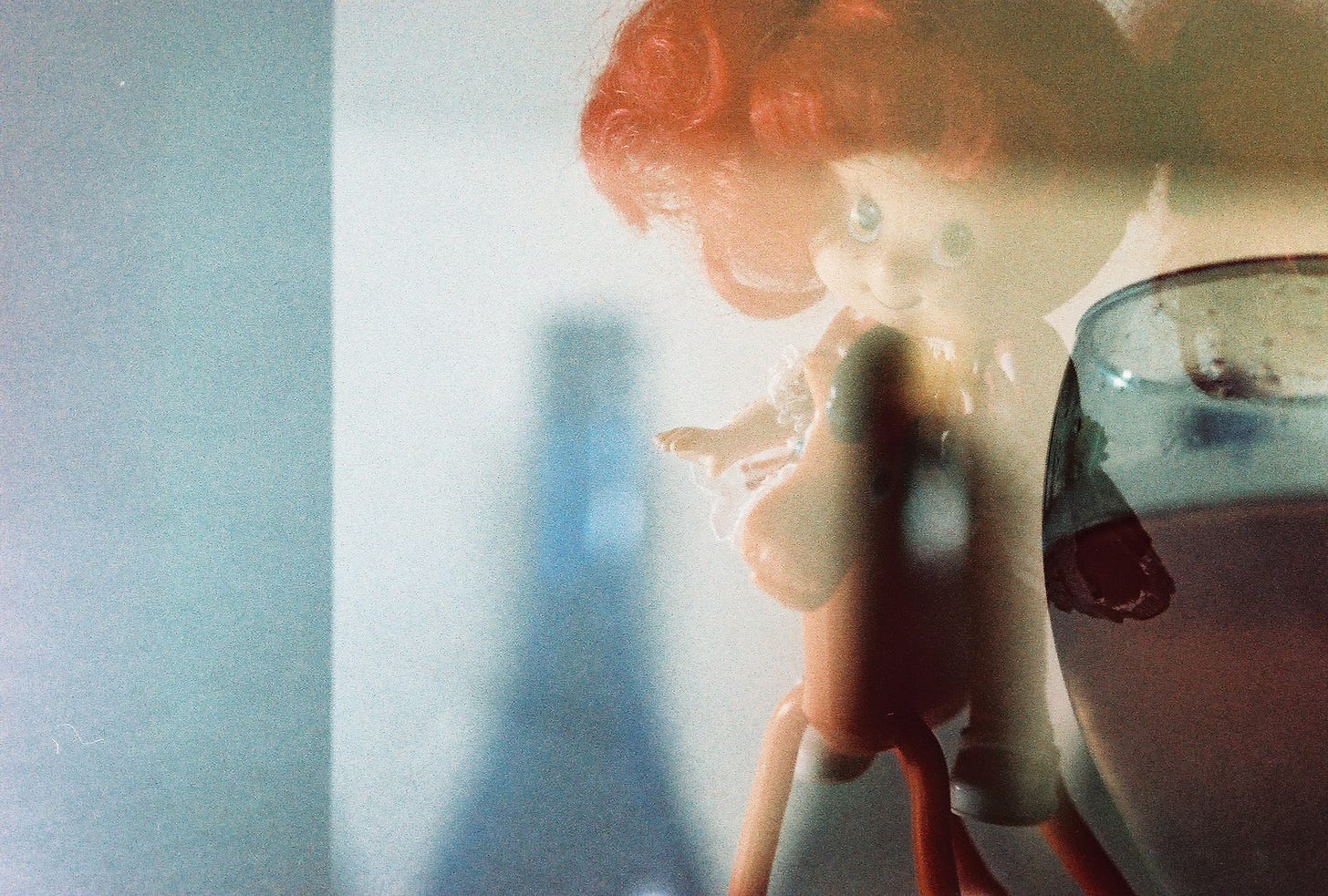 A double exposure shows a Strawberry Shortcake doll sitting on an orange pony, with some glass & wine bottle shapes in the background and foreground.