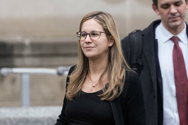 A woman wearing glasses walks outdoors.