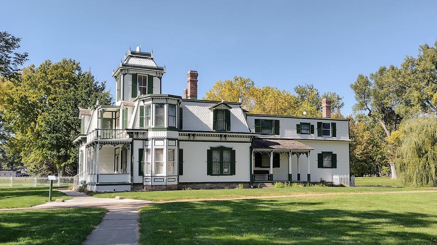 Victorian mansion two stories with turret surrounded by trees 