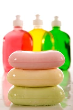 three colorful bars of soap in front of three colorful clear soap dispenser bottles three colorful bars of soap in front of three colorful clear soap dispenser bottles