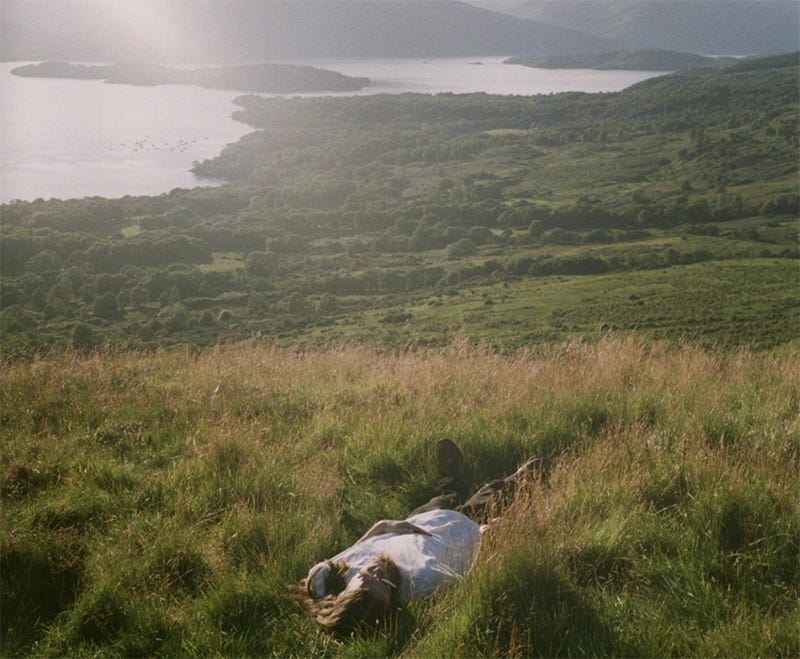 Photo of a person lying peacefully in a field next to a fjord