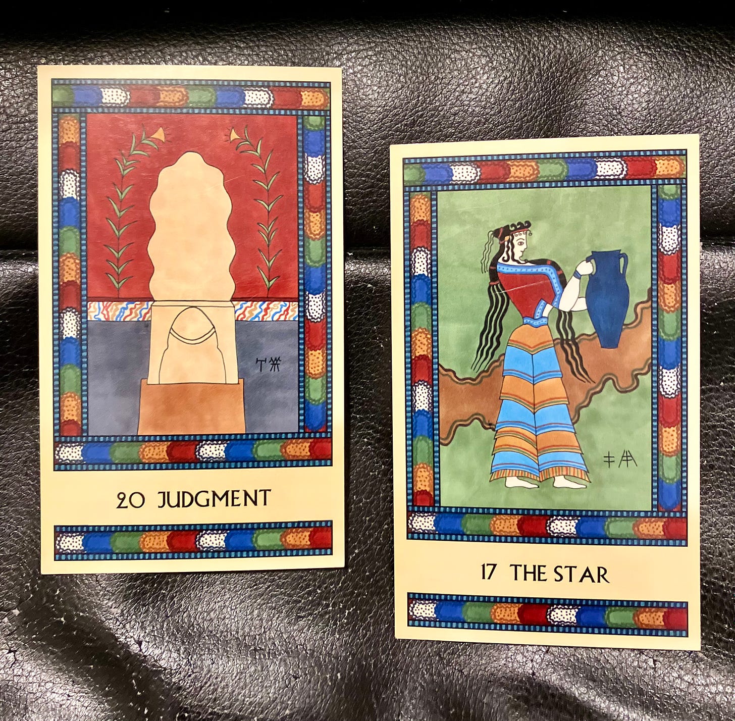 Two Minoan Tarot cards on a shiny black background. Both cards have multicolor borders. Judgment shows the central seat in the Knossos Throne Room, with wall frescoes surrounding it. The Star shows a Minoan woman, facing right, holding a large blue vase. 
