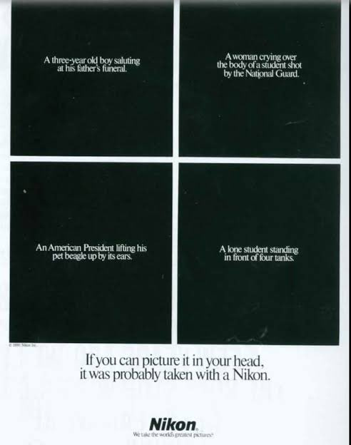 An ad for Nikon shows white text in four black boxes. Box 1 reads: A three-year-old boy saluting at his father’s funeral. Box 2: A woman crying over the body of a student shot by the National Guard. Box 3: An American President lifting his pet beagle up by the ears. Box 4: A lone student standing in front of four tanks. The headline at the bottom reads: If you can picture it in your head, it was probably taken with a Nikon. 