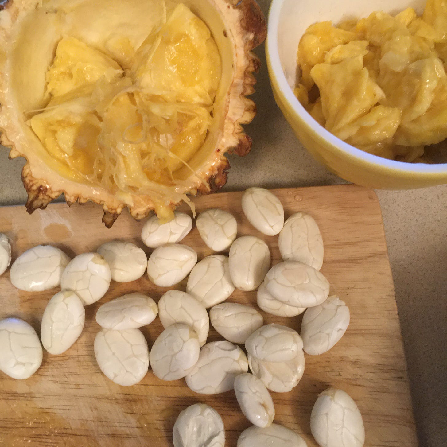Open Theobroma bicolor pod with peeled, raw seeds and a bowl of the fruit
