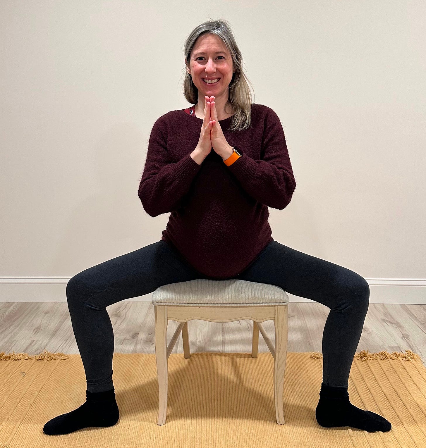 Woman sitting in a chair in a variation of Goddess Pose