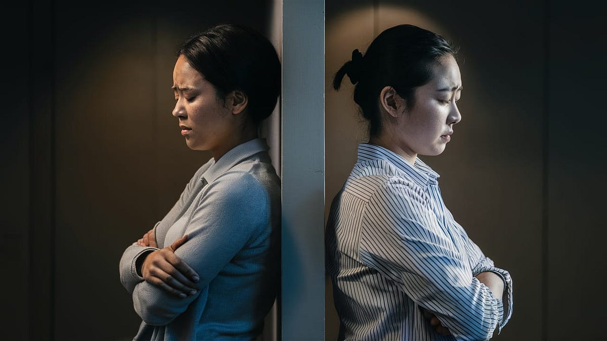 two women back-to-back, separated by a wall