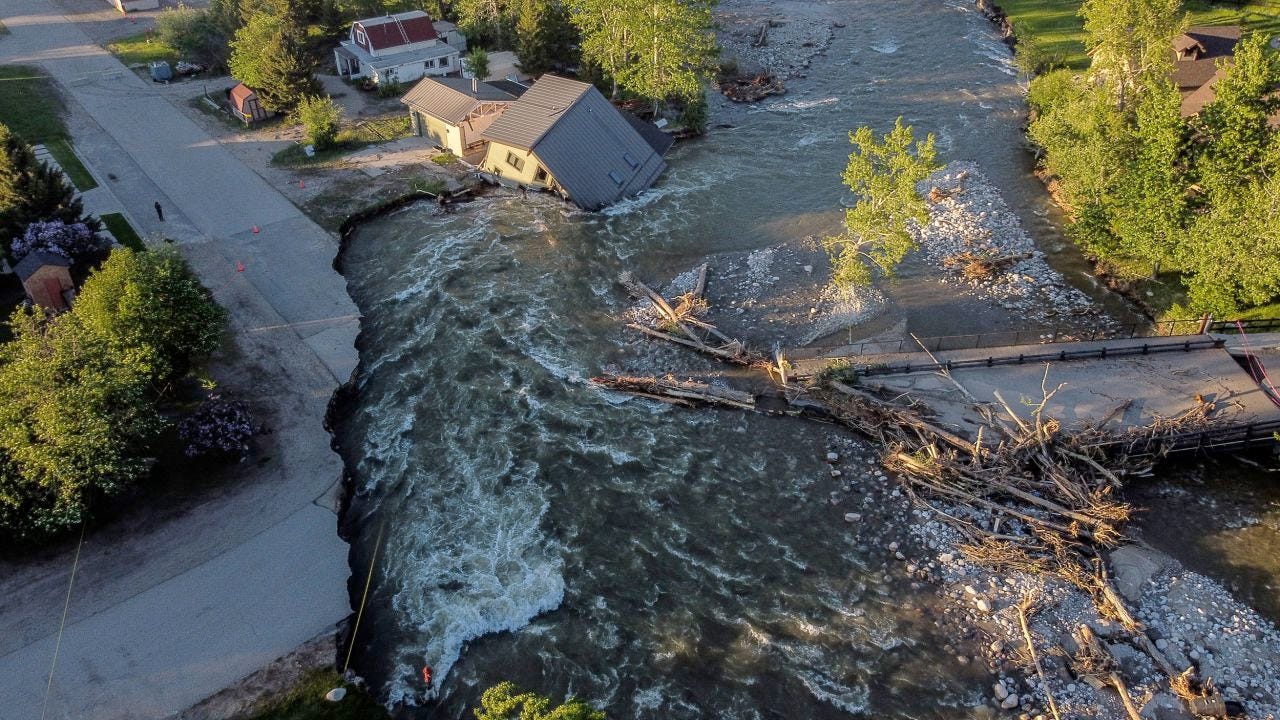 Aerial view of Yellowstone Park and Red Lodge destruction. A house has fallen in the river as the corner of a road was washed away.