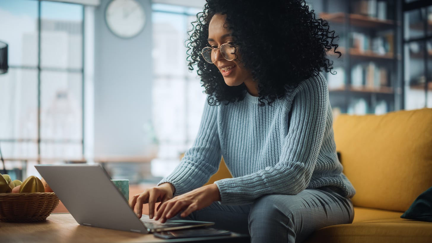 Young woman wearing glasses and looking at her laptop.