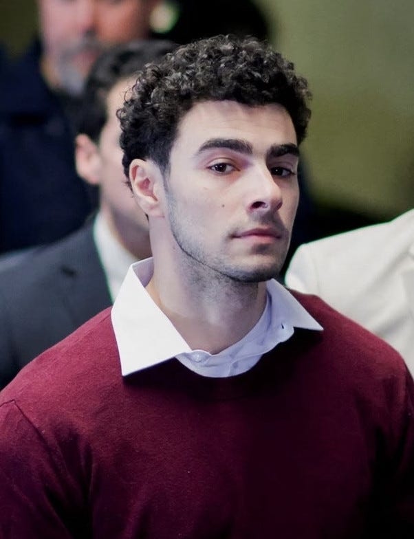 Foto de Luigi Mangione, homem branco com barba e cabelos cacheados castanhos usando blusa branca com sweater vinho