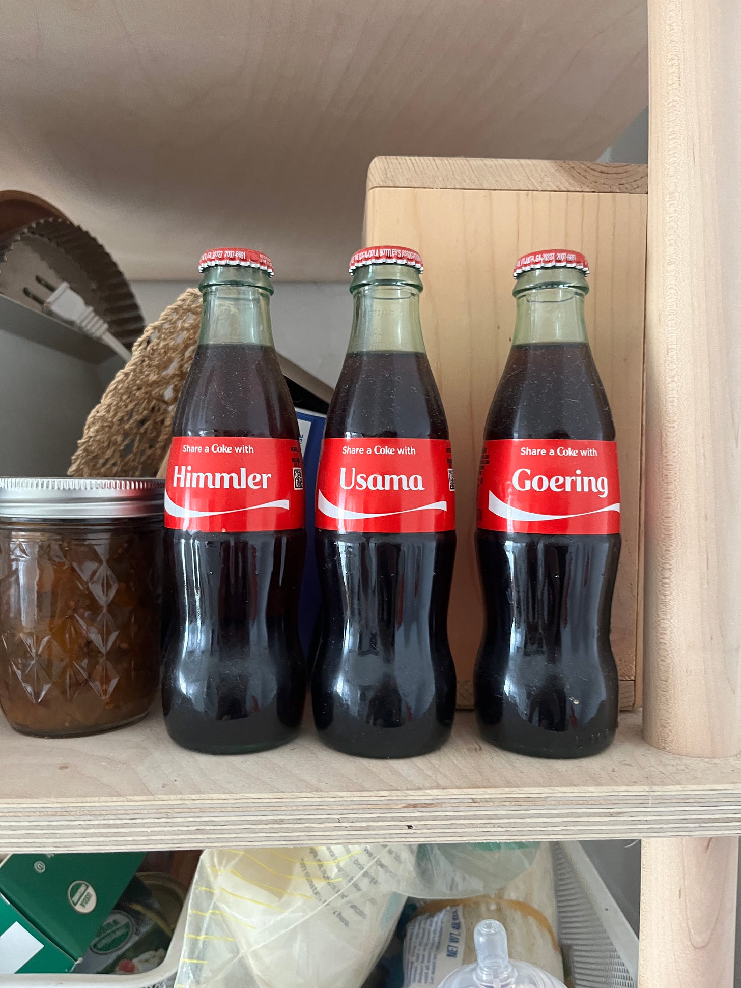 Three glass coke bottles that say "Share a Coke with..." and the names "Himmler," "Usama," and "Goering."