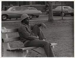Man sitting on a park bench looking to the right side, in black and white