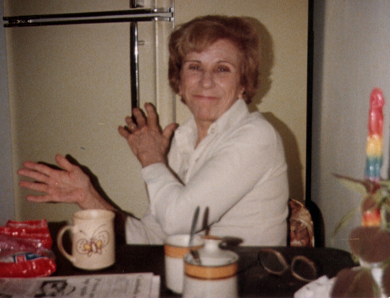 A woman sitting at the kitchen table slapping her hands together and smiling