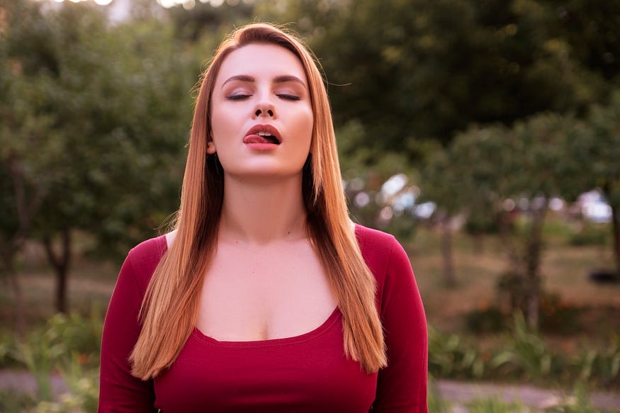 Woman with long reddish hair over shoulders, red dress, cleavage