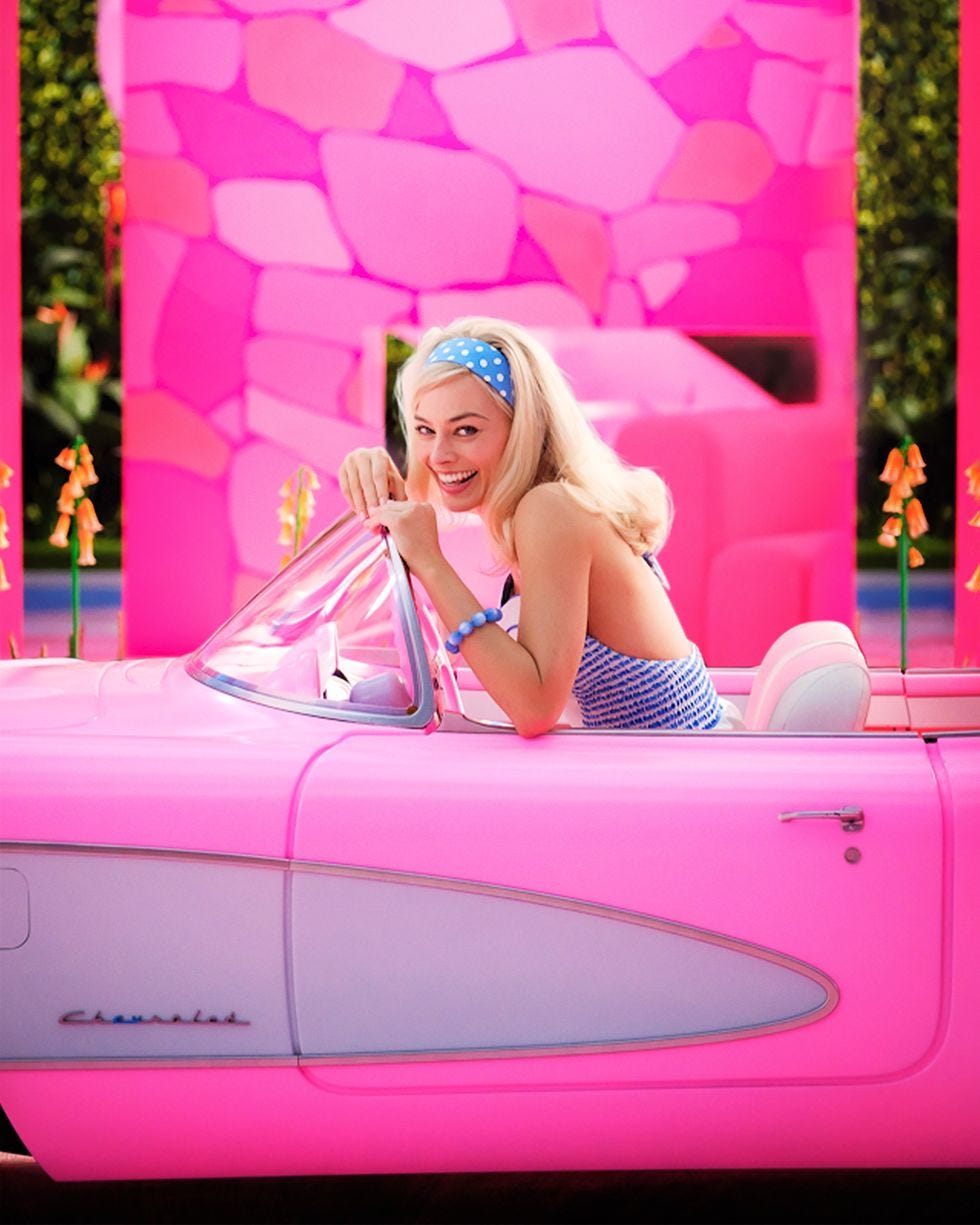 Barbie grinning in her pink car on her bright pink set