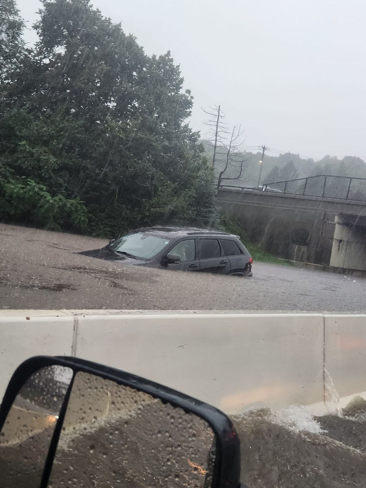 An SUV in Fitchburg, Massachusetts, submerged up to the hood in flood water, stranded on the highway