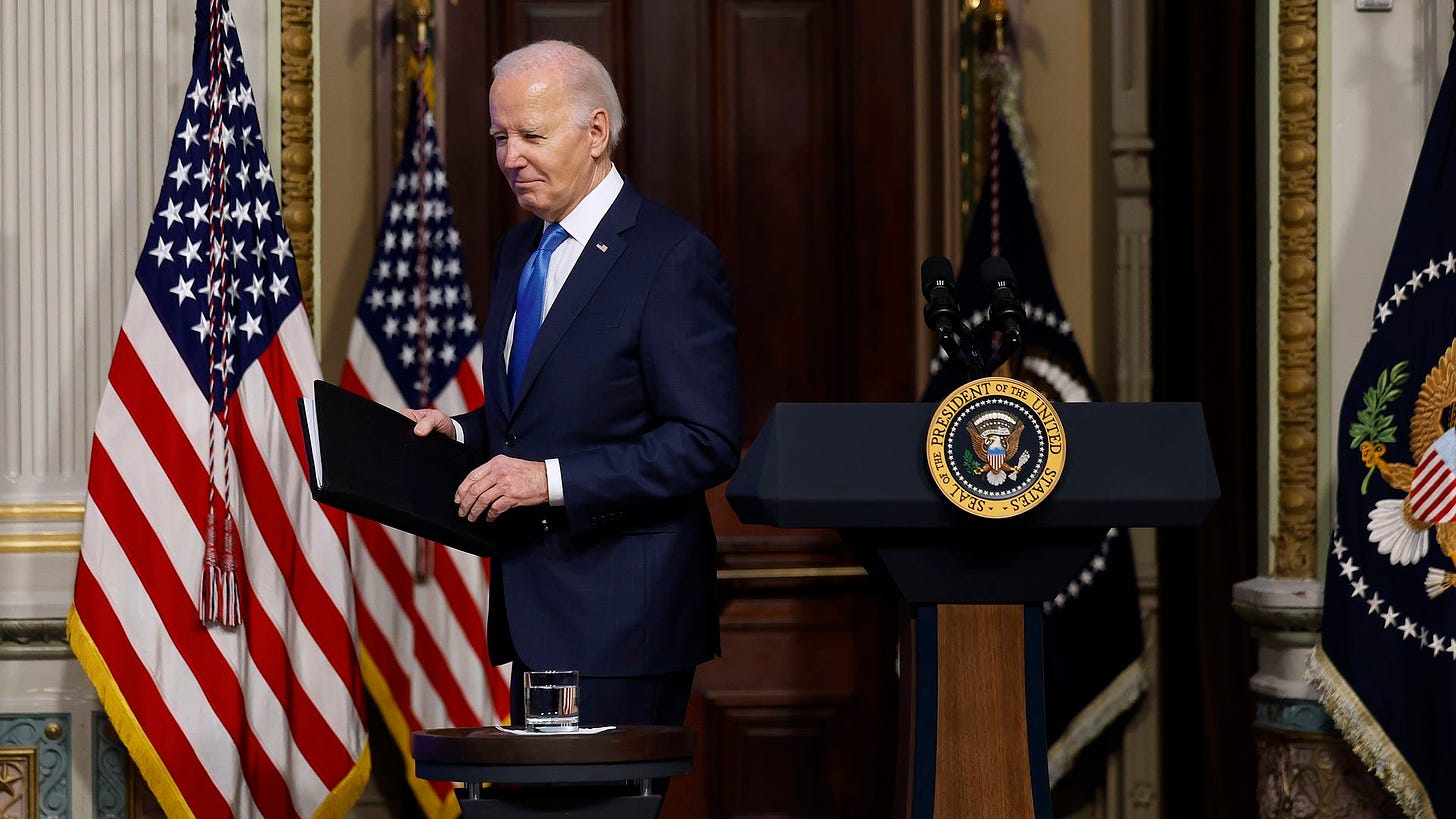 Biden walks behind a lectern with the American flag behind him.