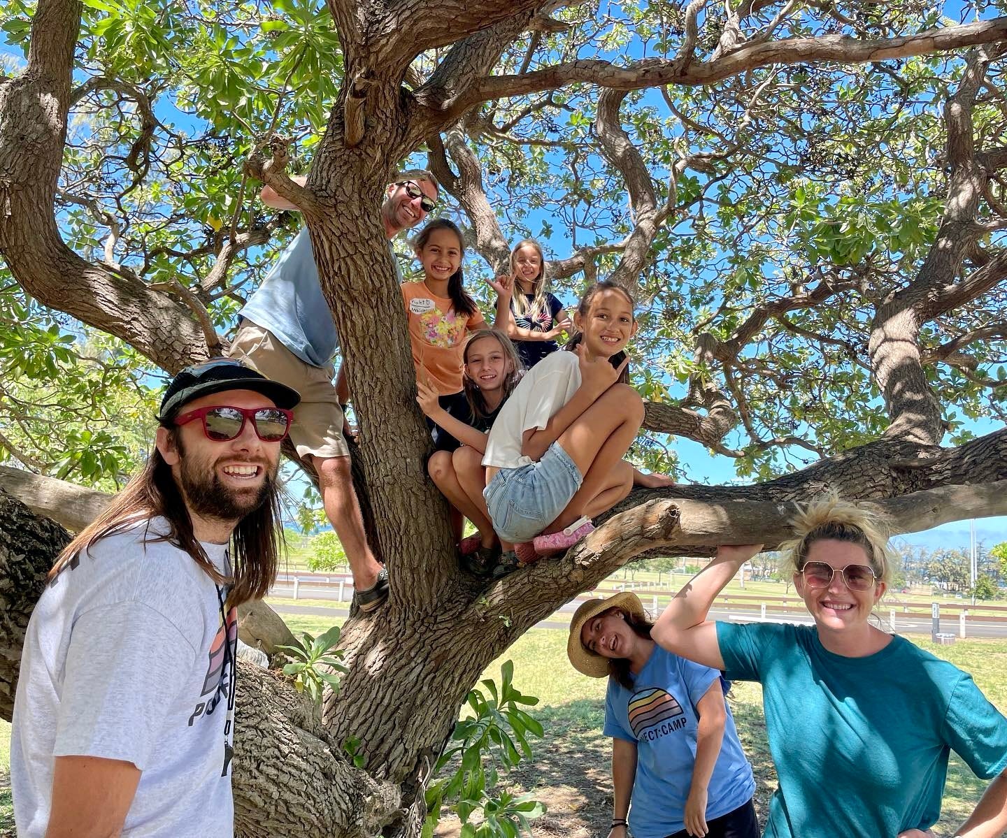 Project:Camp staff, volunteers and kids smiling while climbing a tree