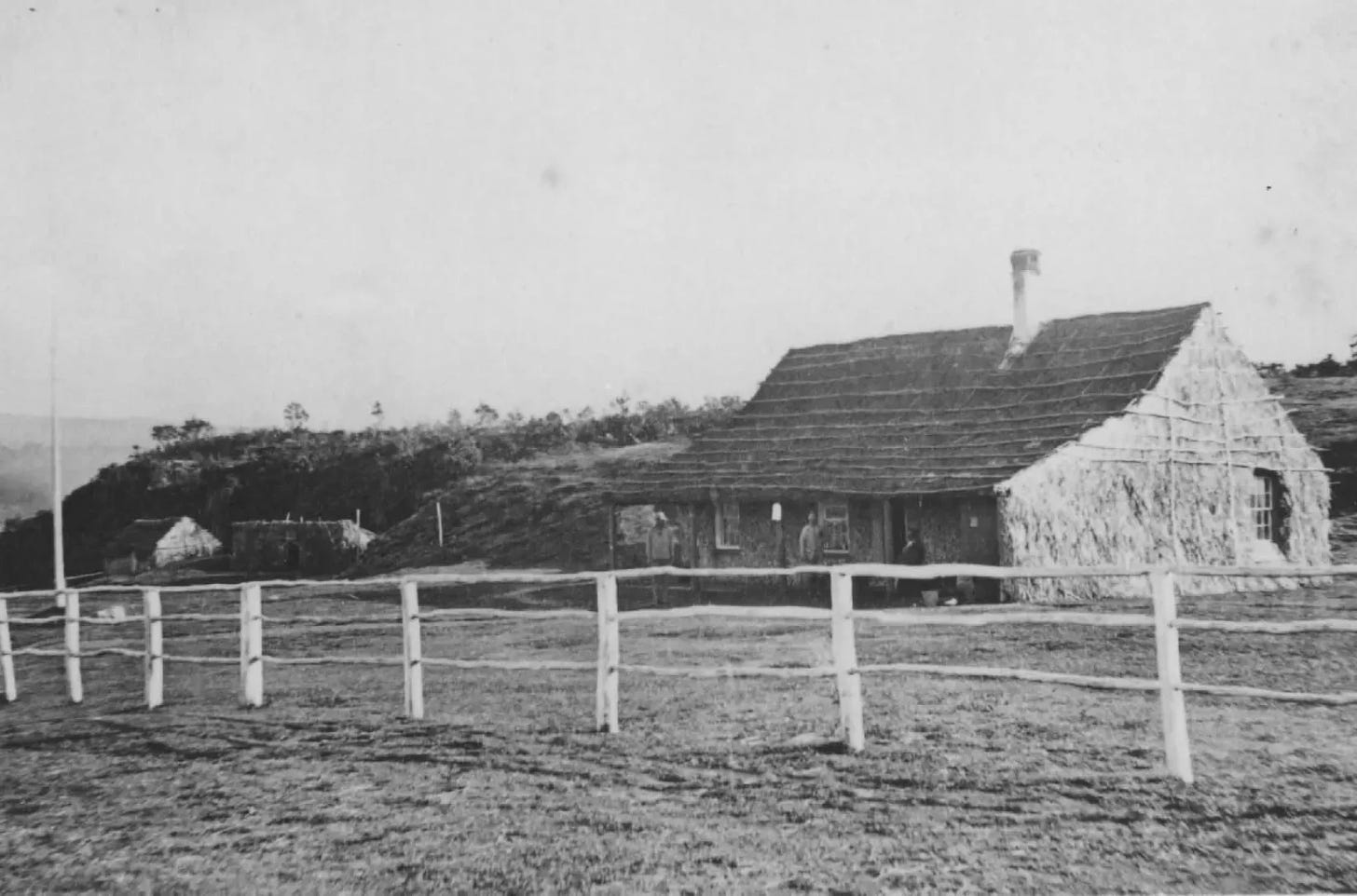 Black and white photo of a spacious bamboo and thatch house