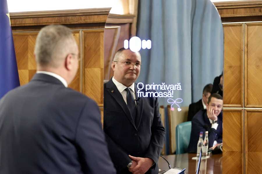 An official photo of Romanian Prime Minister Nicolae Cuica speaking to a mirror with a "ION" logo and the text "O primăvară frumoasă" projected on top.