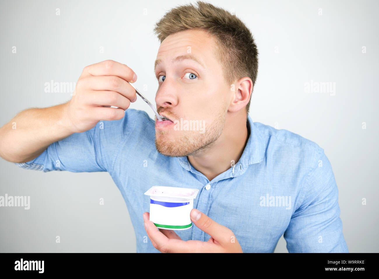 young handsome man putting spoon with yogurt in his mouth on isolated white  background Stock Photo - Alamy