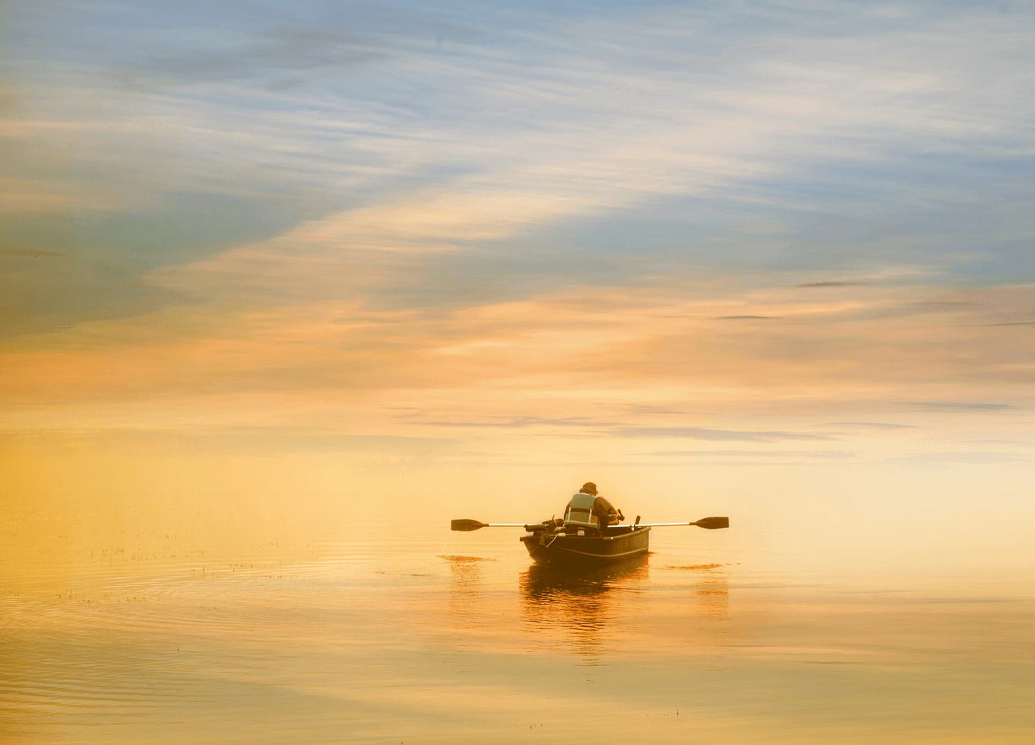 Rowboat with one person out on the water at sunset
