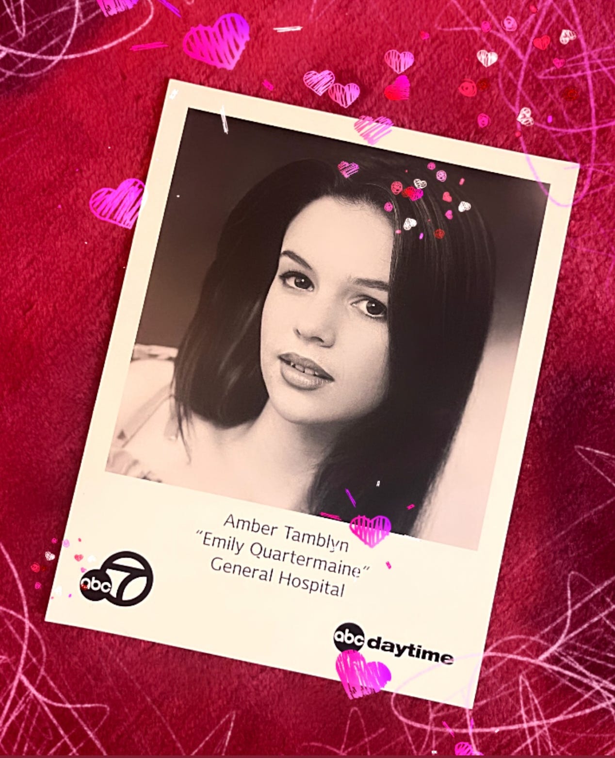 A photo of a black-and-white headshot of a teenage Amber Tamblyn. Text below the headshot reads, "Amber Tamblyn / 'Emily Quartermaine' / General Hospital" Over the entire image, Amber has added a filter of cartoon pink hearts. The ABC 7 logo is in the bottom left corner and ABC Daytime logo is in the bottom right corner.