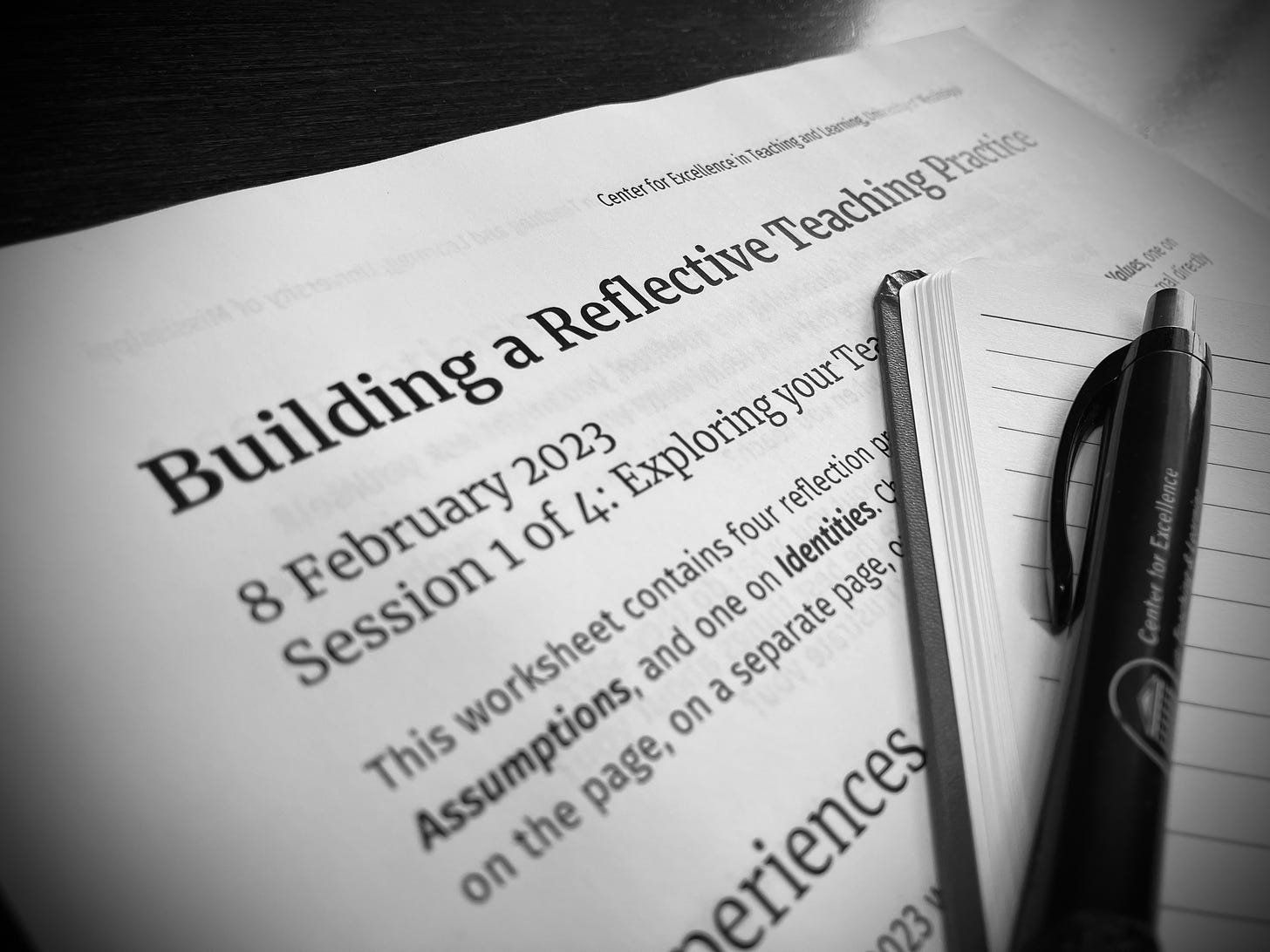 Black and white photograph of a worksheet titled "Building a reflective teaching practice," with a pen and notebook