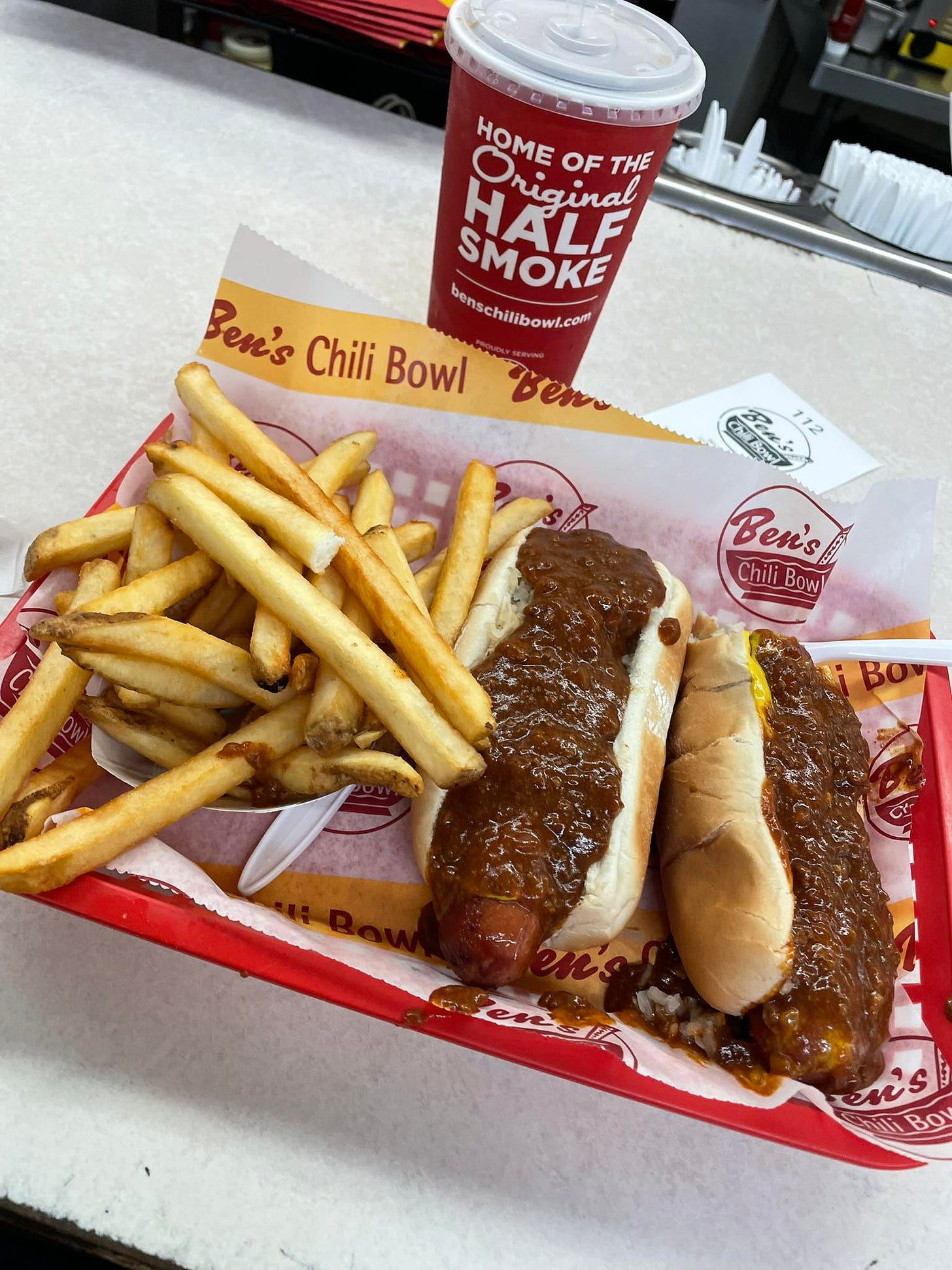 May be an image of hotdog and text that says 'O HOME OF THE HALF Nrginal ricinal SMOKE Ben's Chili Bowl benschilibowl.com Conschitibowl.com Beno Zeow CEMS Bens 12 Ben's Chili ChiliBowl Bow! ns BO'